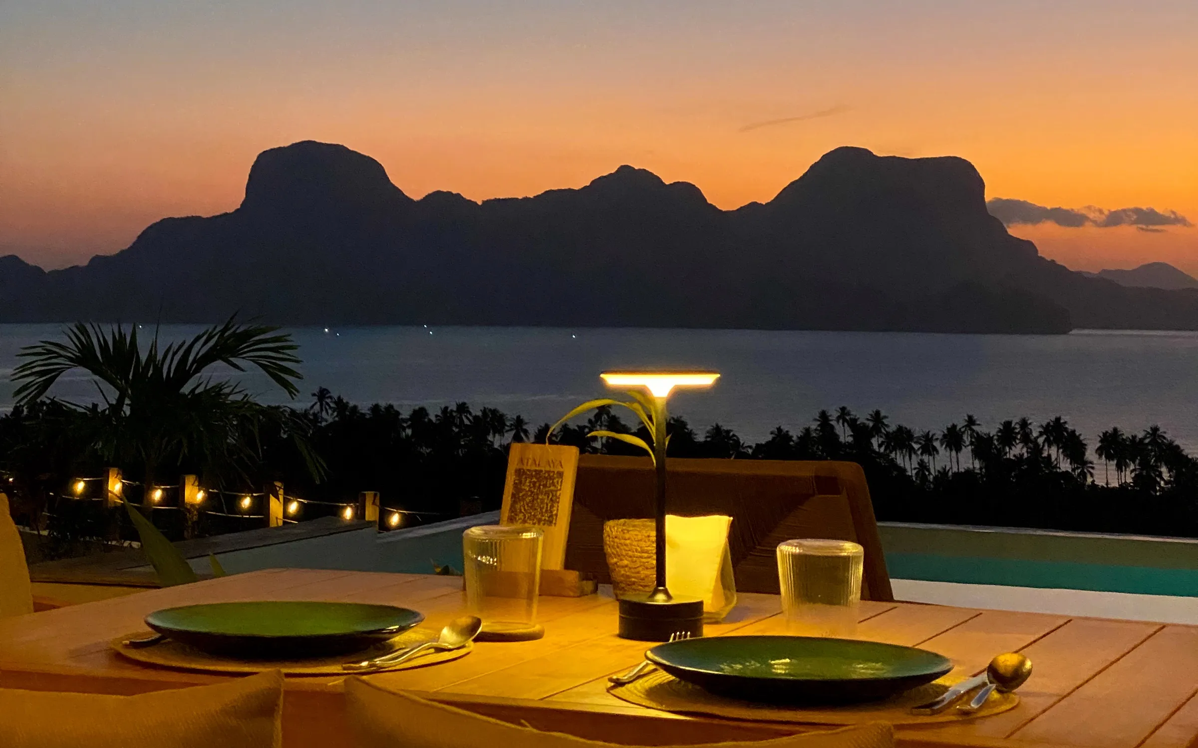 Dinner set on the terrace as the sun goes down over Bacuit Bay